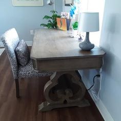 a wooden table with a lamp on top of it next to a chair and window