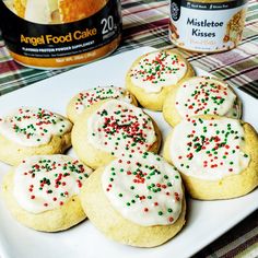 several cookies with white frosting and sprinkles on a plate next to a can of angel food cake