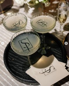 three martini glasses sitting on top of a black tray