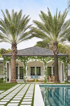 a house with two palm trees in front of it and a swimming pool next to it