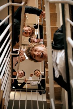 a group of men standing next to each other in front of a mirror on a stair case