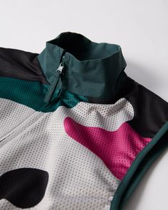 a close up of a jacket on a white surface with pink and green details in it