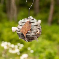 a bird is sitting on top of a hanging bird feeder in the grass and flowers