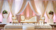 the stage is set up for an event with white and gold chairs, red flowers and greenery