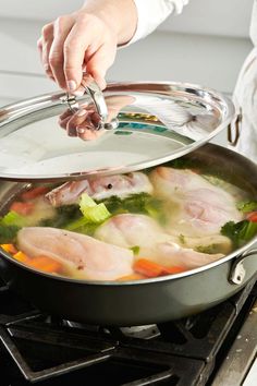 a person is stirring some food in a pot on top of the gas burner