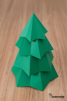 an origami christmas tree made out of green paper on a wooden table top