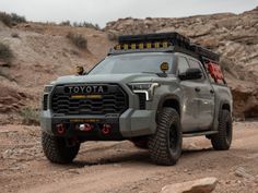 a gray truck driving down a dirt road