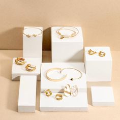 several different types of jewelry on display in white and gold boxes with matching rings, bracelets, and earrings