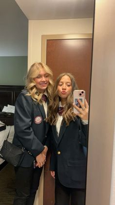 two women standing in front of a mirror taking a selfie