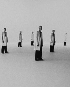 black and white photograph of men standing in the middle of a room with one man wearing a suit