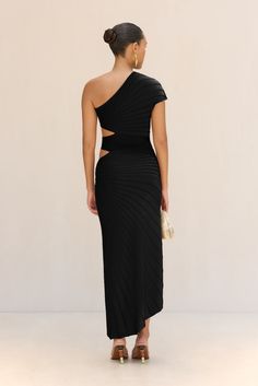 An asymmetrical knit masterpiece, this dress has ribbed sunburst panels with signature Cult Gaia cutouts held together by gold-toned, brushed brass oblong rings at the left side. — Asymmetrical hem — Right covered sleeve — Left side cutouts — Exposed left shoulder — Ribbed knit fabric Sleek Ribbed Party Dress, Modern Black Asymmetrical Evening Dress, Black Ribbed Evening Dress, Modern Black Asymmetrical Party Dress, Icon Clothing, Evening Flats, Sandal Platform, Cult Gaia, Candle Collection