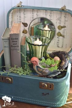 an open suitcase filled with books, candles and other items on top of a wooden table