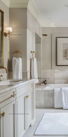 a white bathroom with marble counter tops and gold trim around the bathtub, sink, and mirror