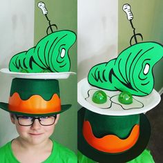 a young boy wearing a green hat with a caterpillar on it