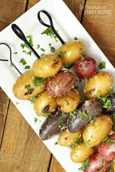 there are many different types of potatoes on the plate with tongs and parsley