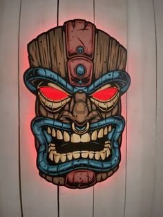 a wooden wall with a tiki mask painted on it's face and red eyes