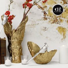 decorative gold vases with flowers and candles on a table next to an old book