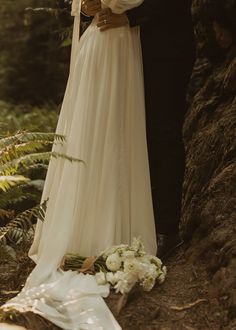 a bride and groom standing next to each other in the woods