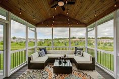 a screened porch with couches, tables and ceiling fans on the outside side of it