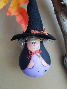 a painted rock with a witch's hat on it next to an autumn tree branch