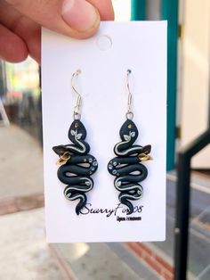 These beautiful and mysterious snake earrings are the perfect addition to any witchy outfit. Casual or fancy, they're great for any occasion from a masquerade ball to a midnight seance. They are also small, light, and made with sterling silver so they are great for sensitive ears.  100 percent of my profits go to charity - I donate to different places, but they all relate to helping animals or the earth. Some charities I often donate to are 8 Billion Trees and Wayward Ranch Animal Sanctuary! Your purchase will help these amazing organizations achieve their goals. Please look them up to learn more! *This item is handmade - each item may look slightly different.* Whimsical Black Drop Earrings, Nickel-free Black Polymer Clay Jewelry, Unique Black Hypoallergenic Jewelry, Whimsical Black Earrings With Ear Wire, Whimsical Black Jewelry For Gifts, Unique Black Snake-shaped Jewelry, Animals Polymer Clay, Floral Snake, New Paltz Ny