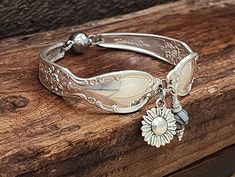 a close up of a bracelet on top of a wooden table with a flower charm