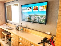 a flat screen tv mounted to the side of a wall next to a wooden desk