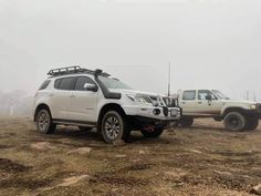 two trucks parked in the middle of a field on a foggy day with no one around them