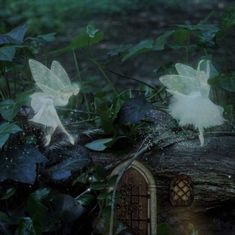 two fairy tinkerbells sitting on top of a log in the woods next to plants