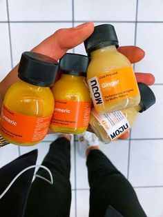 a person holding three bottles of orange juice