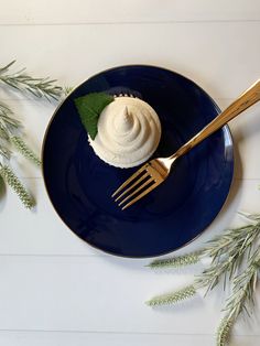 a blue plate topped with a desert on top of a wooden table next to greenery