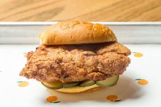 a fried chicken sandwich with cucumbers on a bun