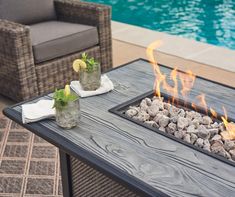 an outdoor fire pit with rocks and lemons on it next to a swimming pool