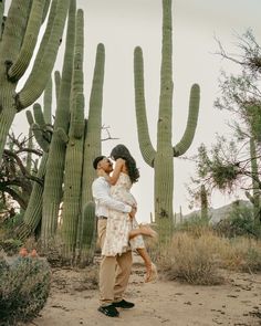 a man and woman kissing in front of cacti on a desert landscape with cactus trees