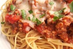 a plate of spaghetti with meat sauce and parmesan cheese on top, garnished with fresh basil