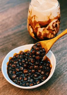 a wooden spoon in a bowl filled with blackberries next to a jar of ice cream