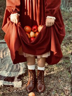 a woman in a red dress holding a basket of apples with her hands on her hips