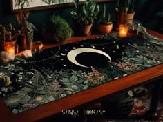 a table topped with plants and candles on top of a wooden table covered in fabric