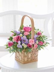 a basket filled with flowers sitting on top of a white table next to a window