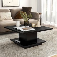 a black coffee table sitting on top of a rug in front of a couch and window