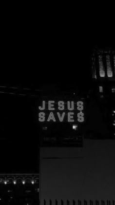 a black and white photo of the jesus saves sign in front of a building at night