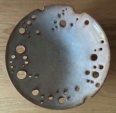 a metal plate with holes in it sitting on a table next to a wooden surface