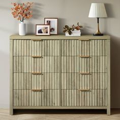 a dresser with several drawers and pictures on top, along with a lamp next to it