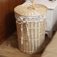 a wicker laundry basket with a lid on the floor next to a white sink