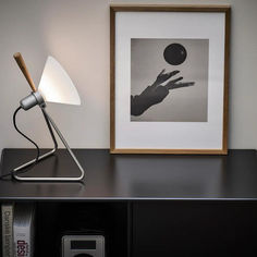 a lamp sitting on top of a black table next to a framed photo and book