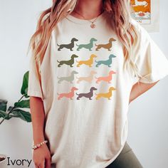 a woman standing in front of a plant wearing a t - shirt with dachshunds on it