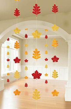 a room with wooden floors and colorful fall leaves hanging from it's ceiling in front of a window