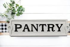 a sign that says pantry on it next to a potted plant and plaid ribbon