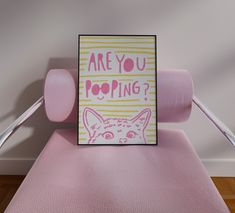 a pink chair with a card on it that says are you pooping? in front of an image of a cat