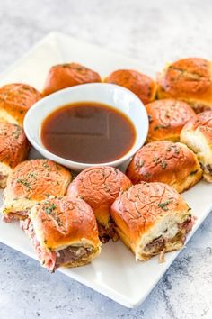 a white plate topped with mini sandwiches and dipping sauce